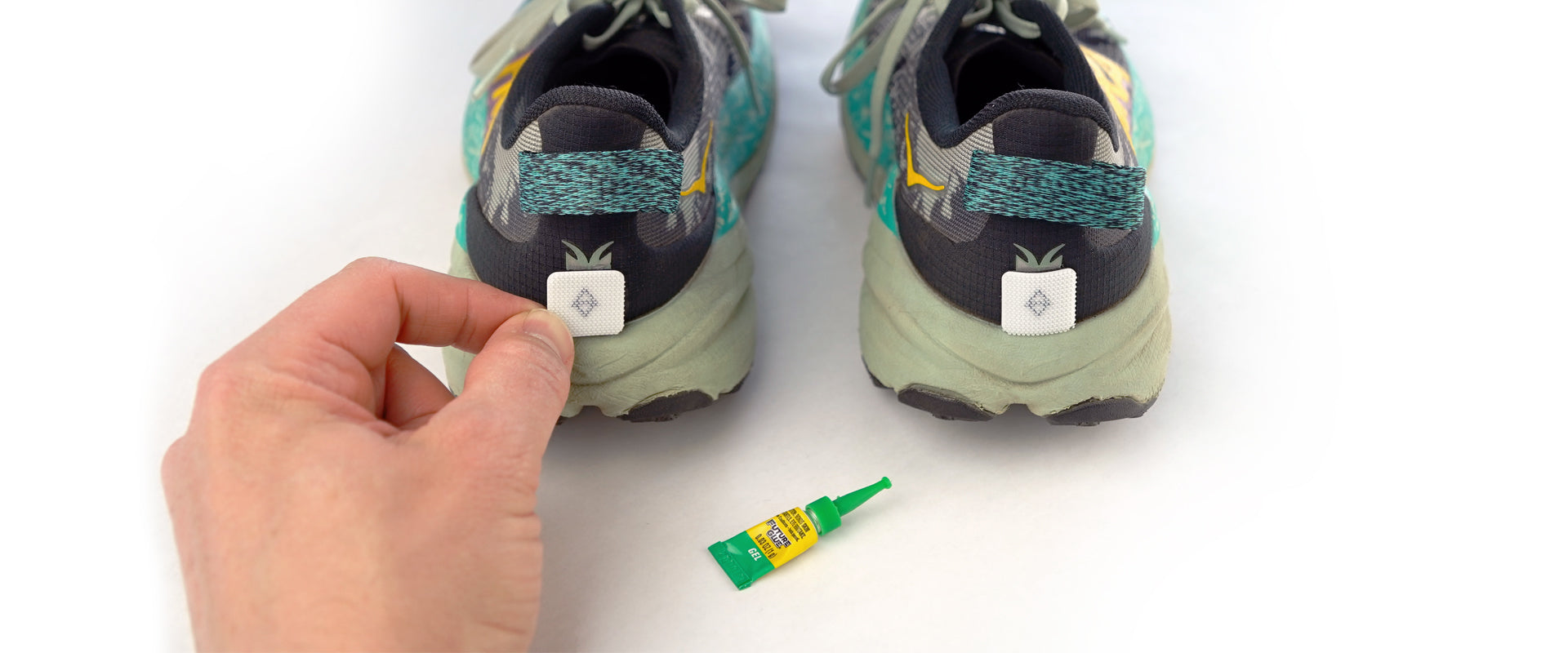 Two sneakers with trado gaiter grips and a small bottle of glue on a white background.